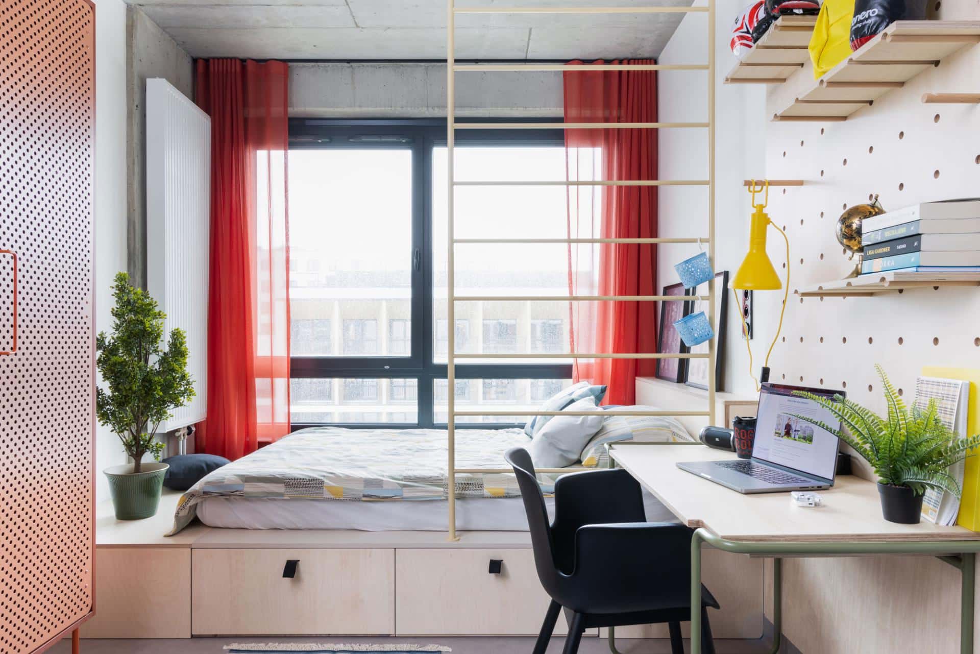 Bed with a large window in a studio room at Basecamp Katowice dorm