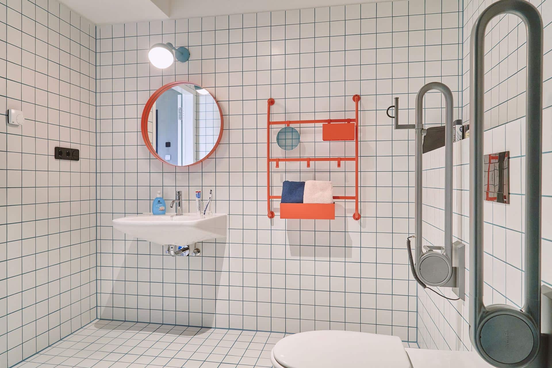 Fully accessible bathroom with mirror, sink, toilet and shower in a studio accessible room at Basecamp Leipzig student accommodation