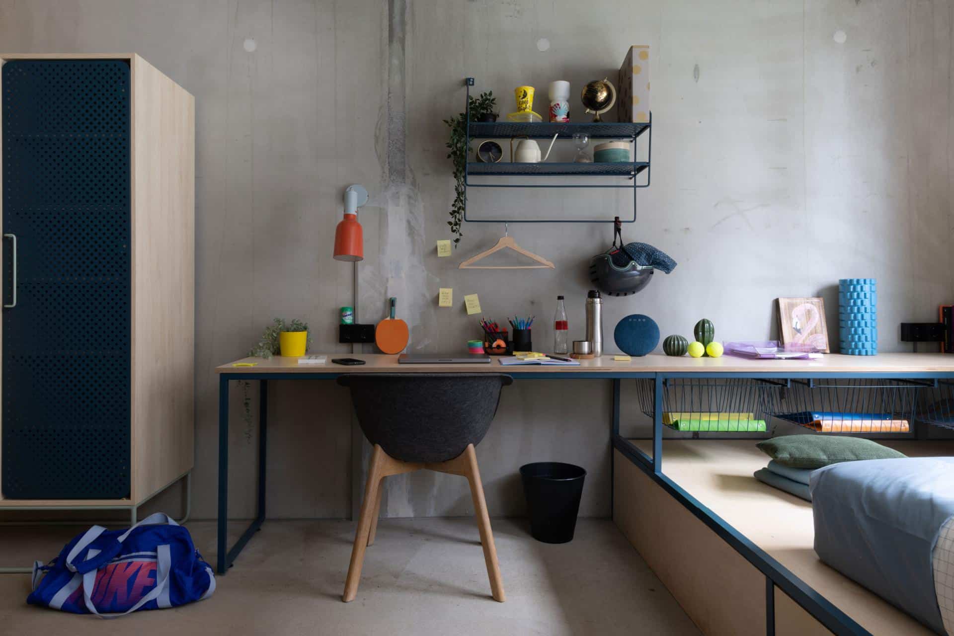 private study area of a studio room in Basecamp Potsdam with large desk, shelves and storage area