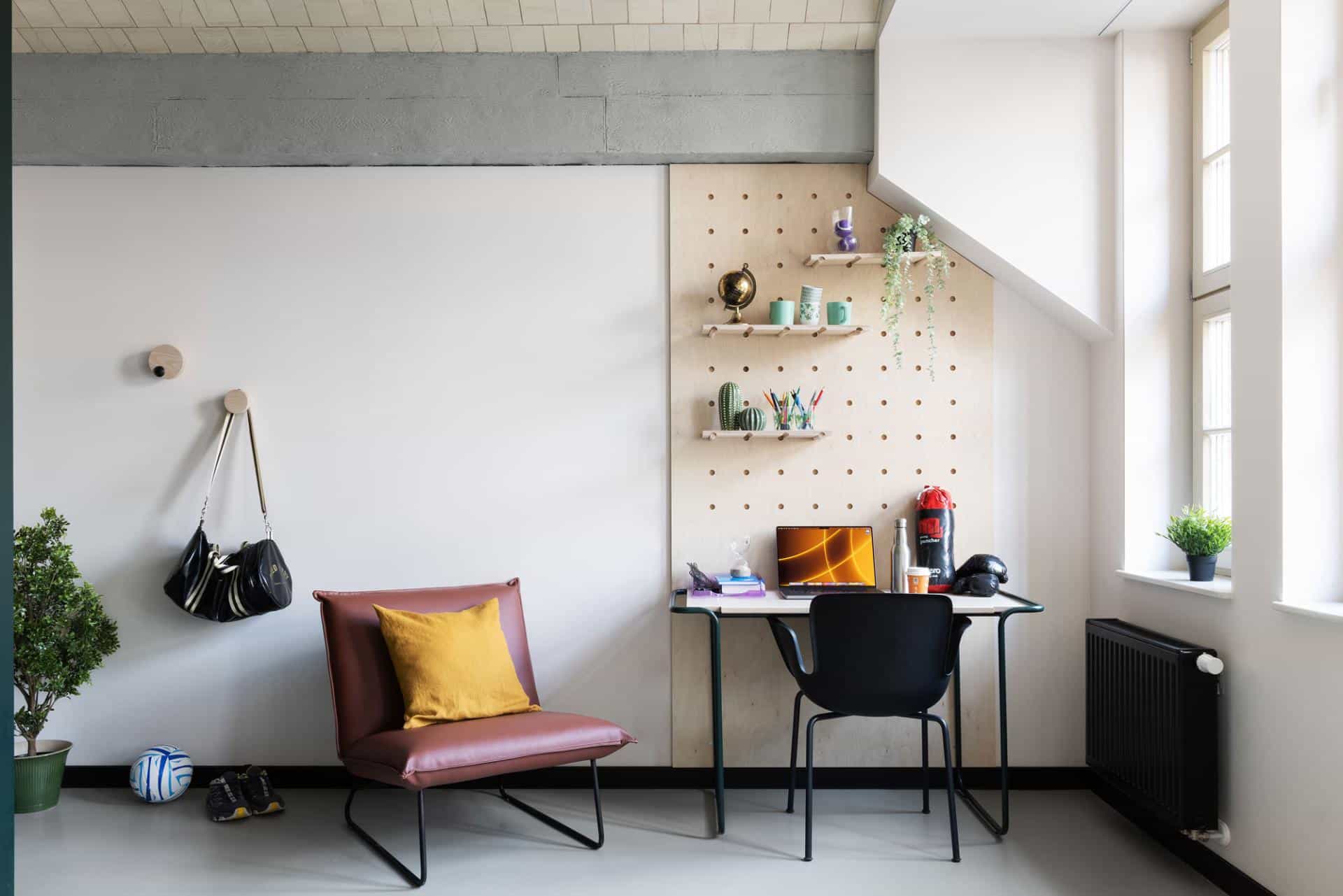 Private lounge area with desk, chair, radiator and large window in single room at Basecamp Wroclaw