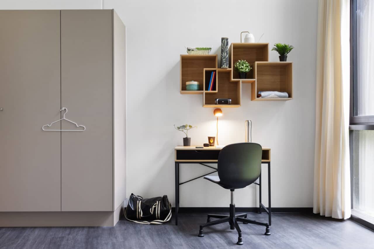 View of a large room for students at Basecamp Lyngby showing a study area with desk and chair