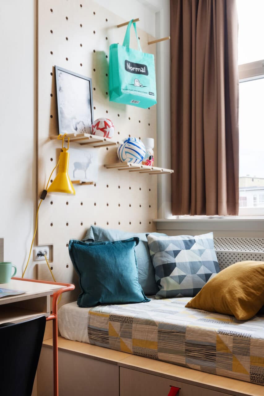 Colourful and modern bed and shelves in a single room at Basecamp Soutch Campus dorm