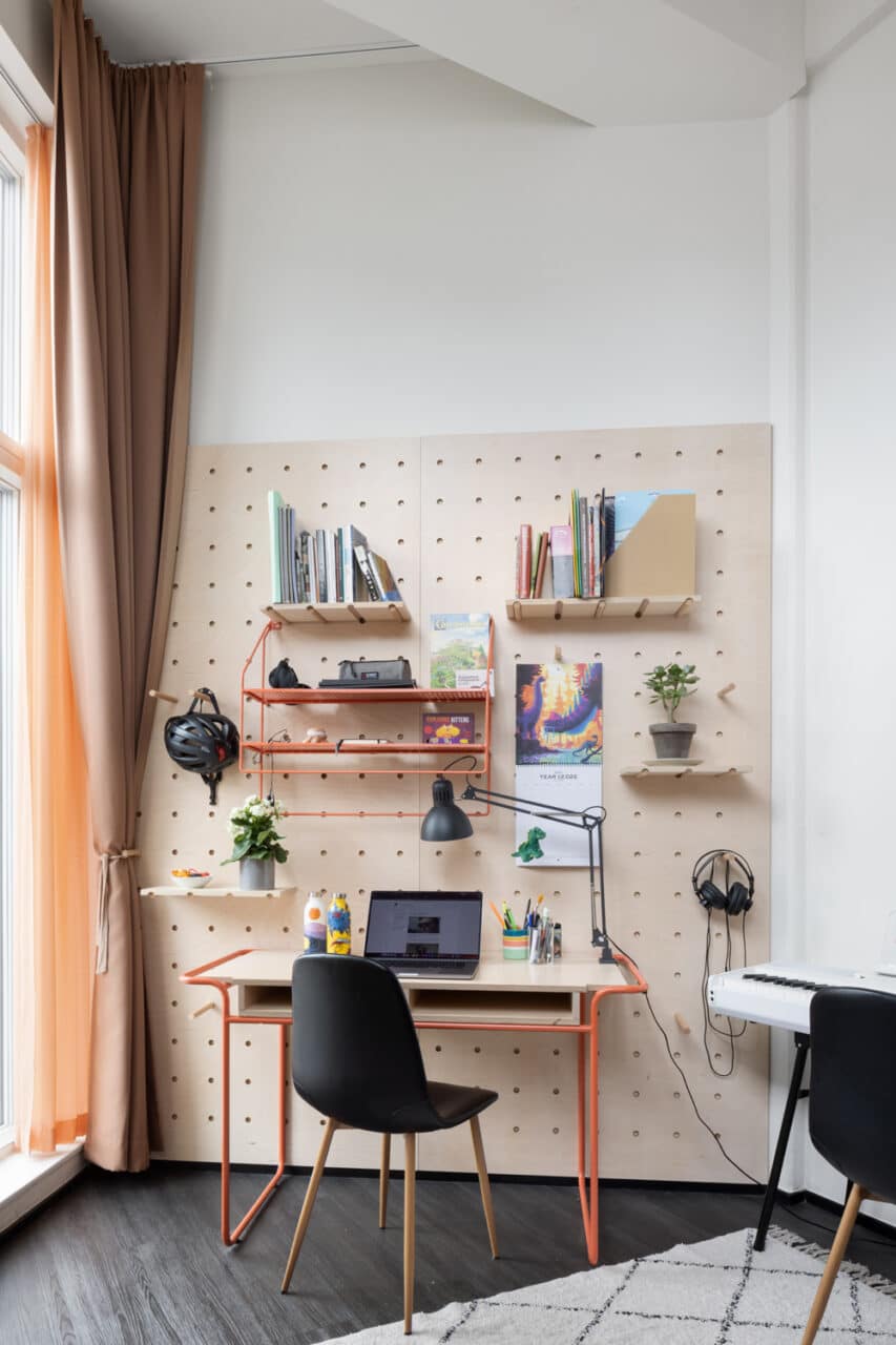 desk and shelves with books in a study area of a private student room in Basecamp Copenhagen South Campus dorm