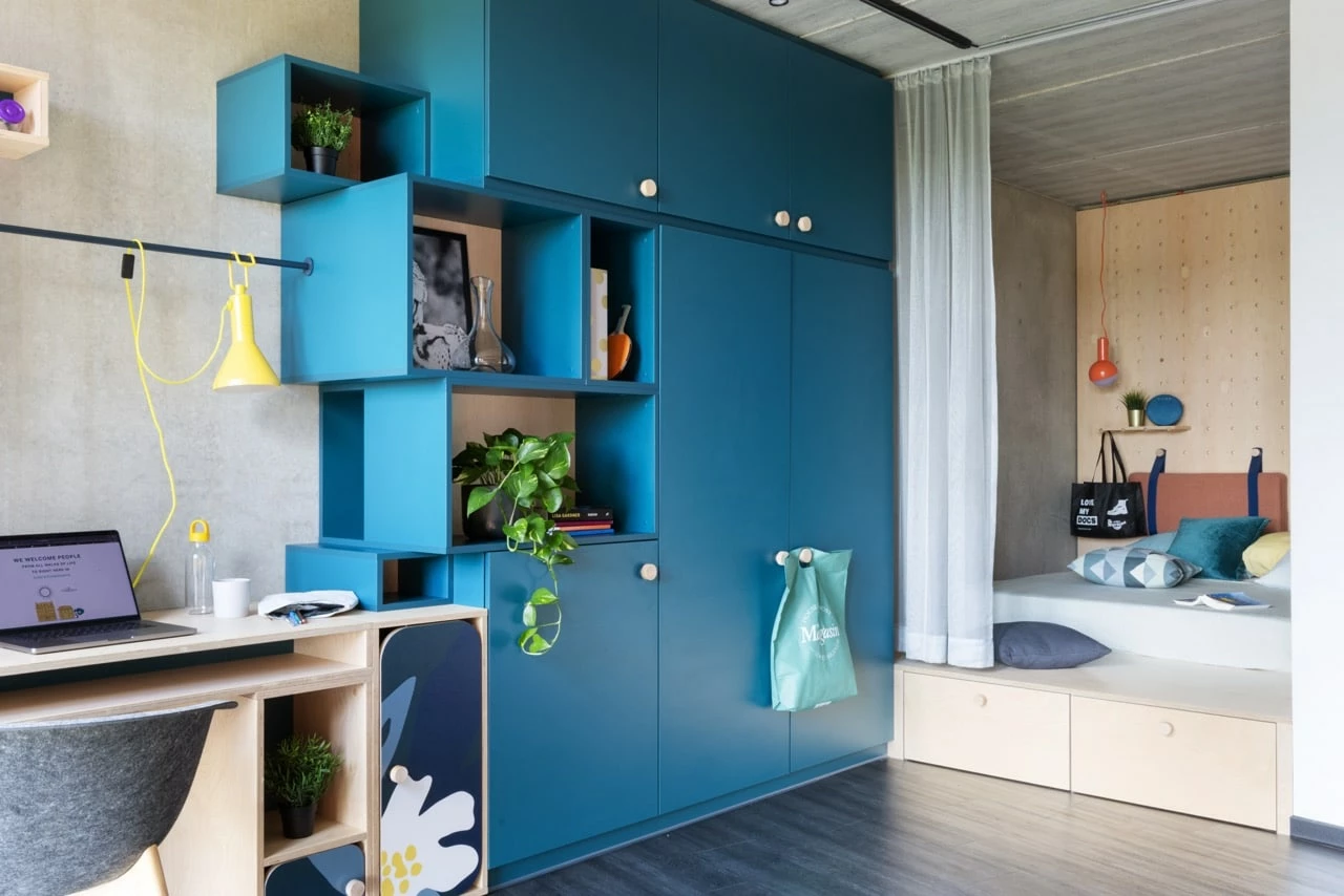 View of a large room for students at Basecamp Lyngby student dormitory showing a study area and bed