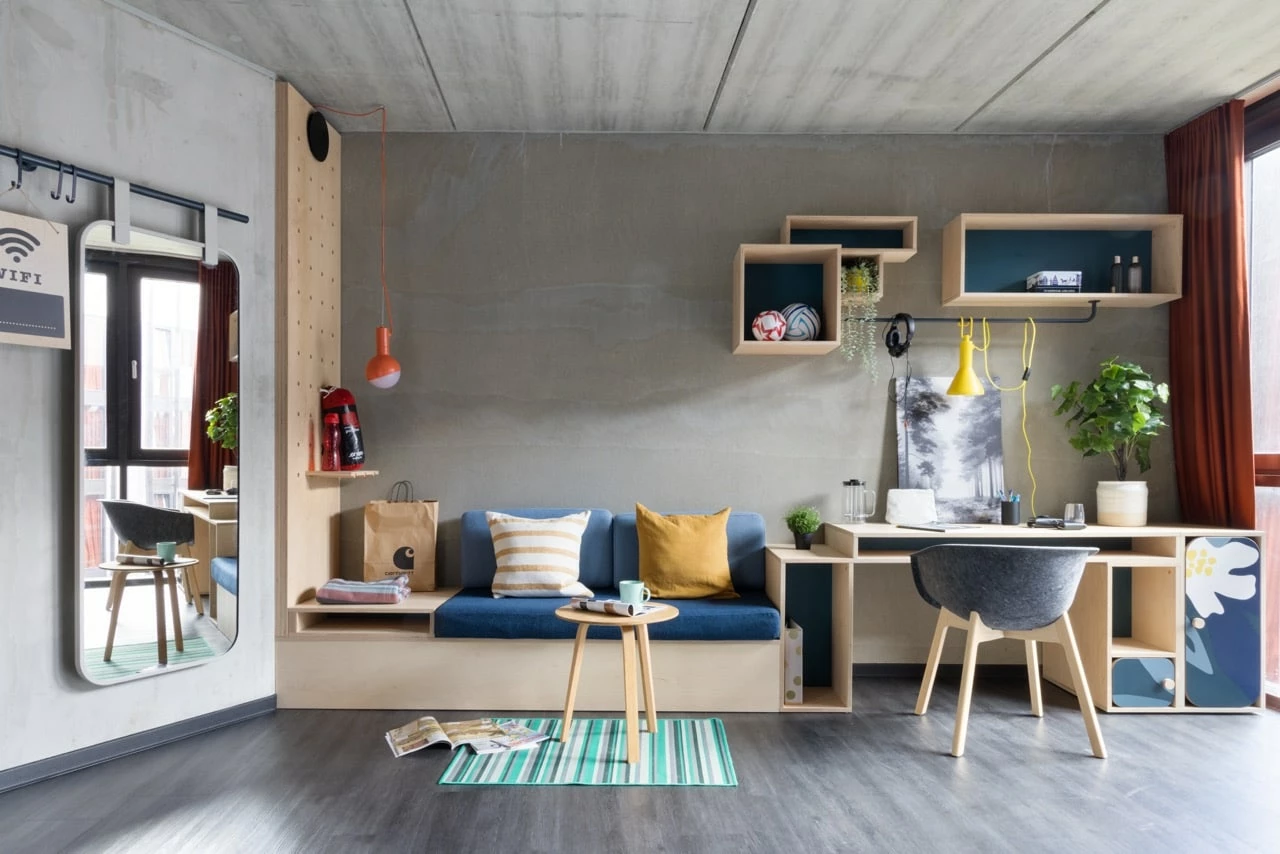 View of a large room for students at Basecamp Lyngby showing the lounge area and study area with desk and chair