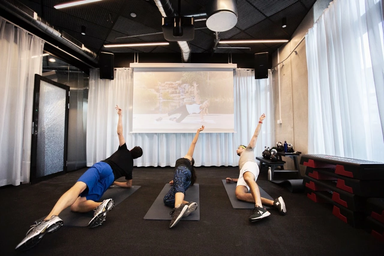 students strecth following a digital coach in the gym at Basecamp Lyngby student dormitory