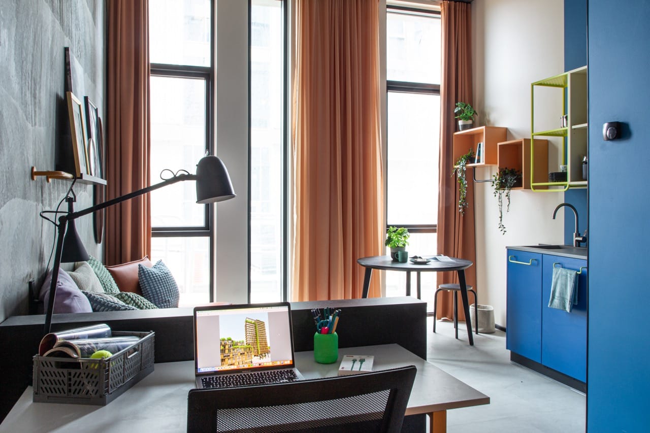 View of a large studio room for students at Basecamp Aarhus showing the lounge area, kitchenette and dining table and study area with desk and chair