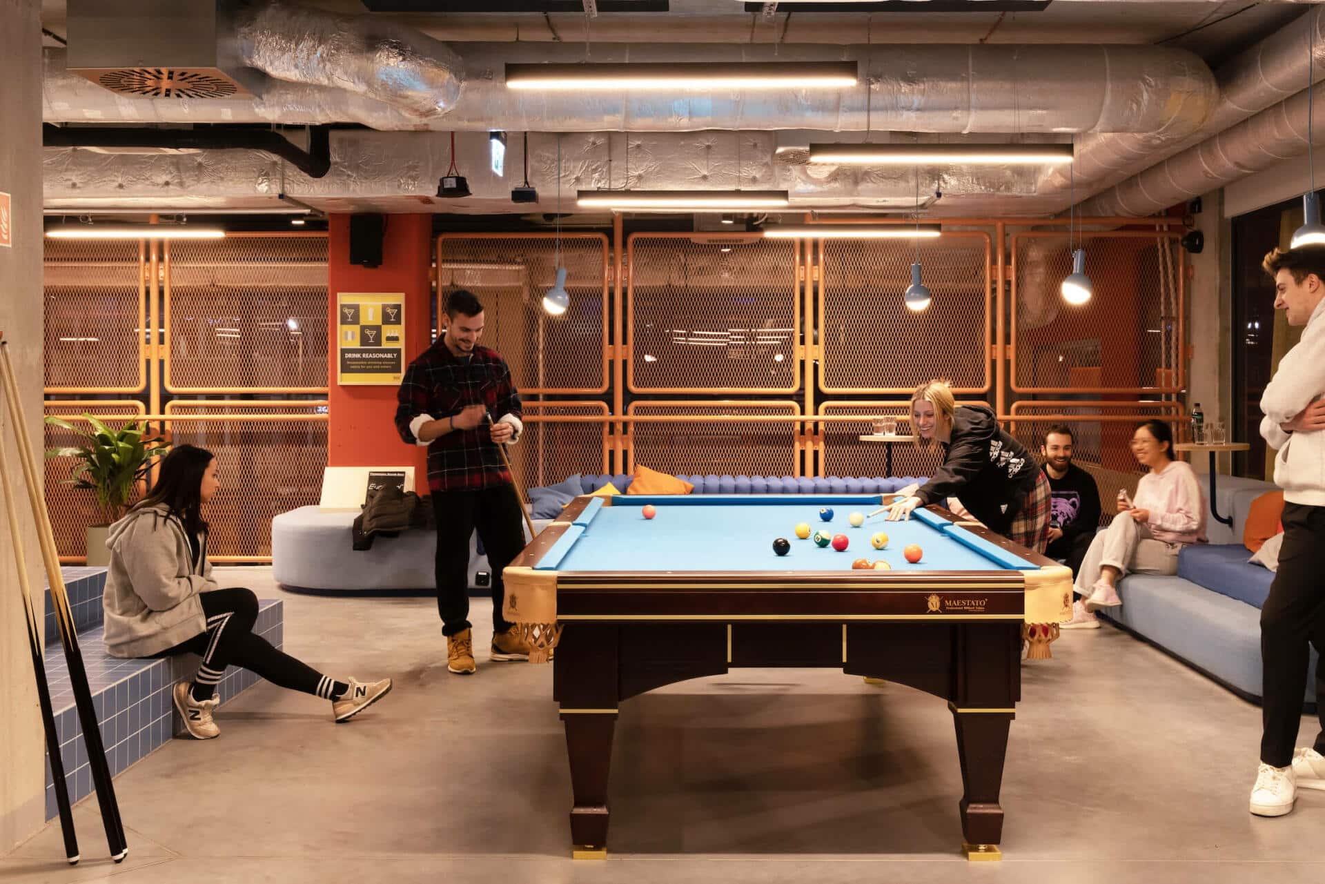 Students enjoy the pool table at an event space at Basecamp Katowice dormitory