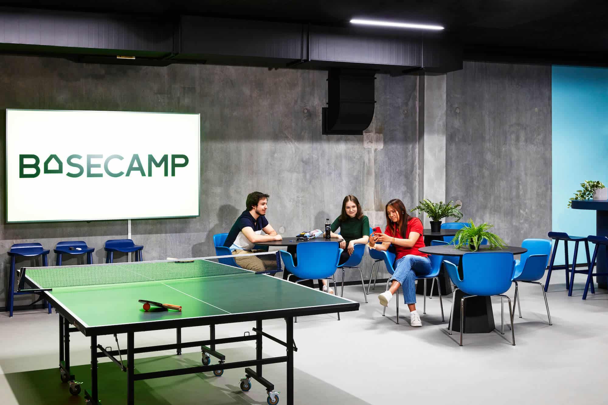 Student residents sitting in one the event spaces with a table tennis table at Basecamp Malmö student housing