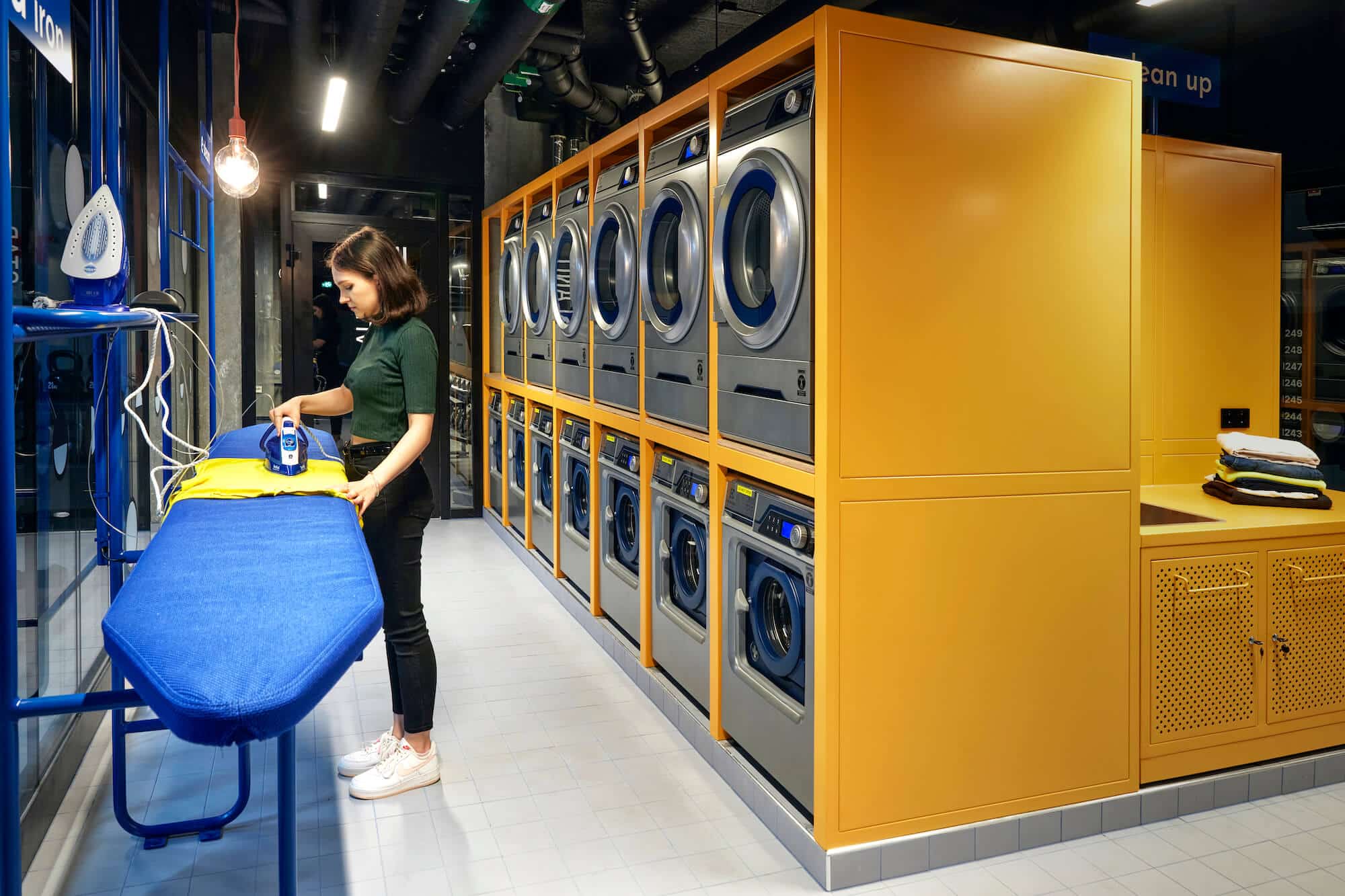 Student ironing in the laundry room at Basecamp Malmö student housing