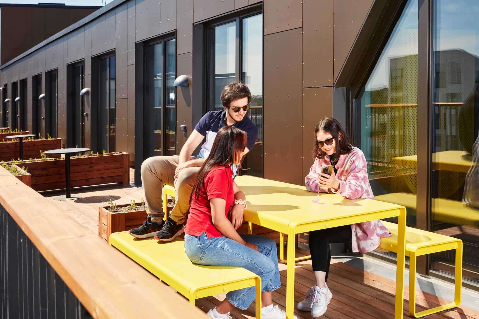 three students enjoying the communal rooftop terrace at Basecamp Malmö student accommodation