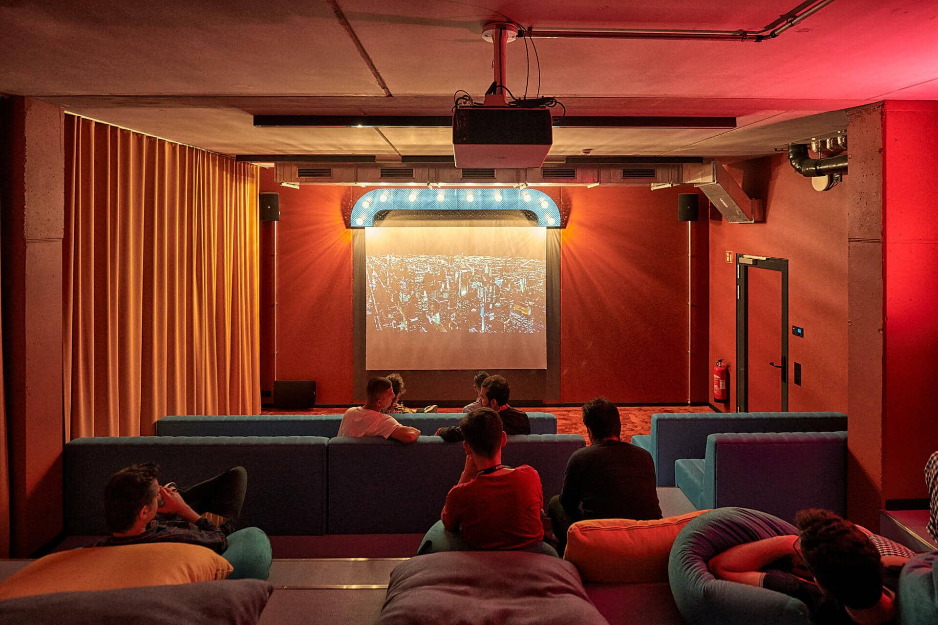 Students relaxing on sofas and watching a movie at Basecamp Gottingen student accommodation cinema room