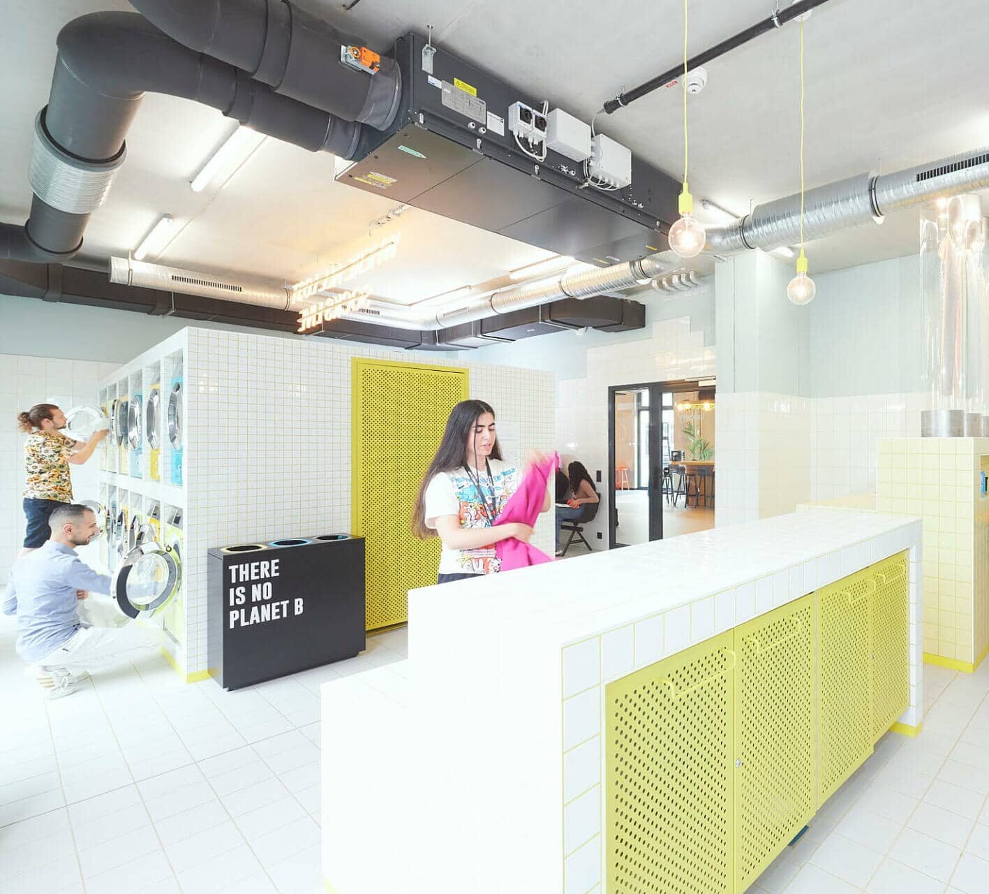 Students using washing machines and tumble dryers in the 24/7 laundry room at Basecamp Gottingen student accommodation