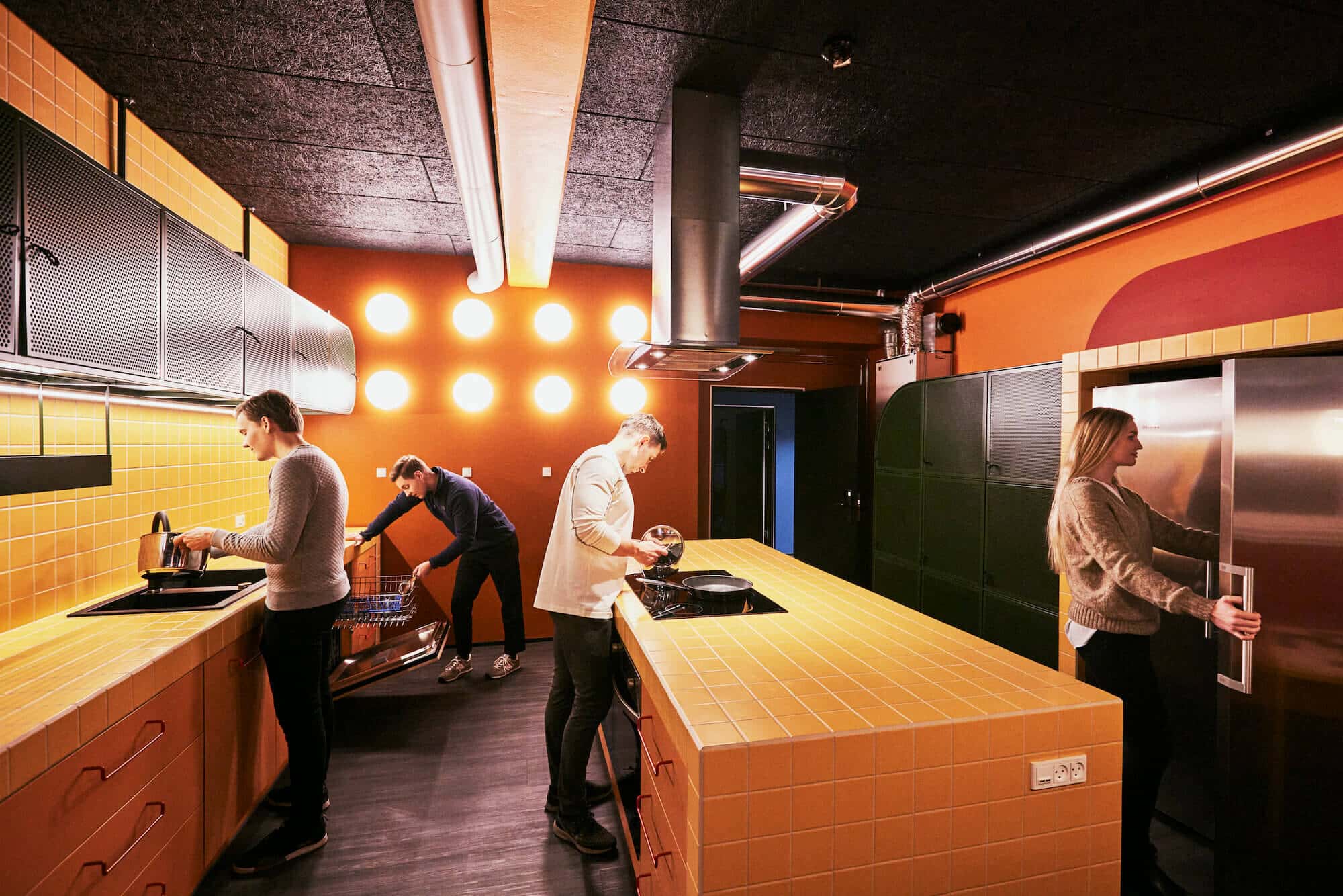 Four students cooking in the communal kitchen at Basecamp Copenhagen South Campus student accommodation