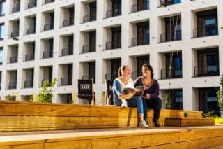 Two people sitting on the steps in the outside area of Basecamp Łódź Rembielińskiego Student housing