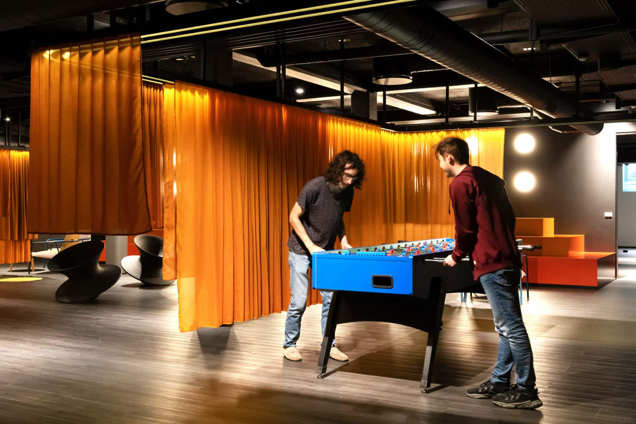 Four people playing foosball in the game zone at Basecamp Copenhagen South Campus Student housing