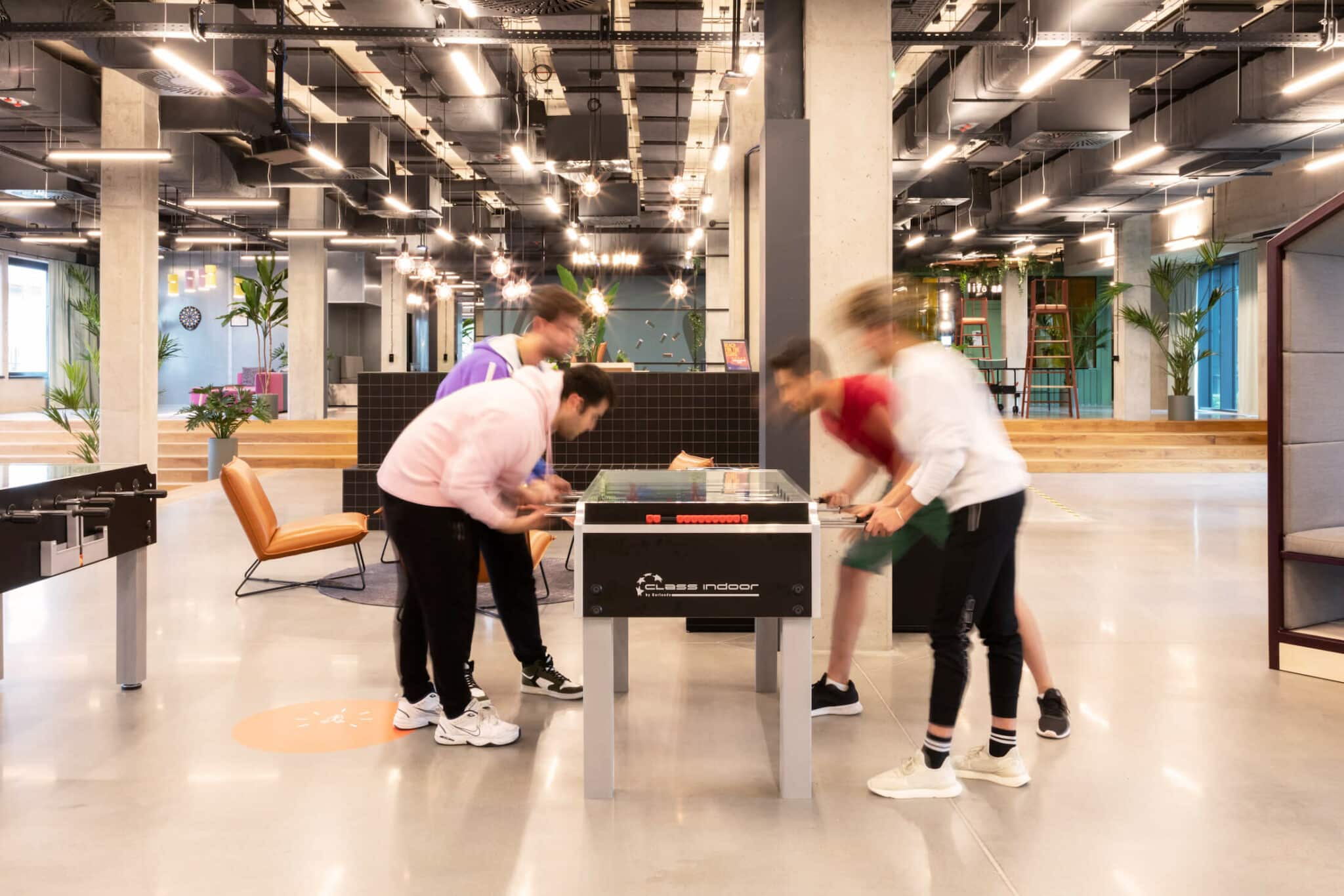 Four people playing foosball in the game zone at Basecamp Łódź Rembielińskiego Student housing