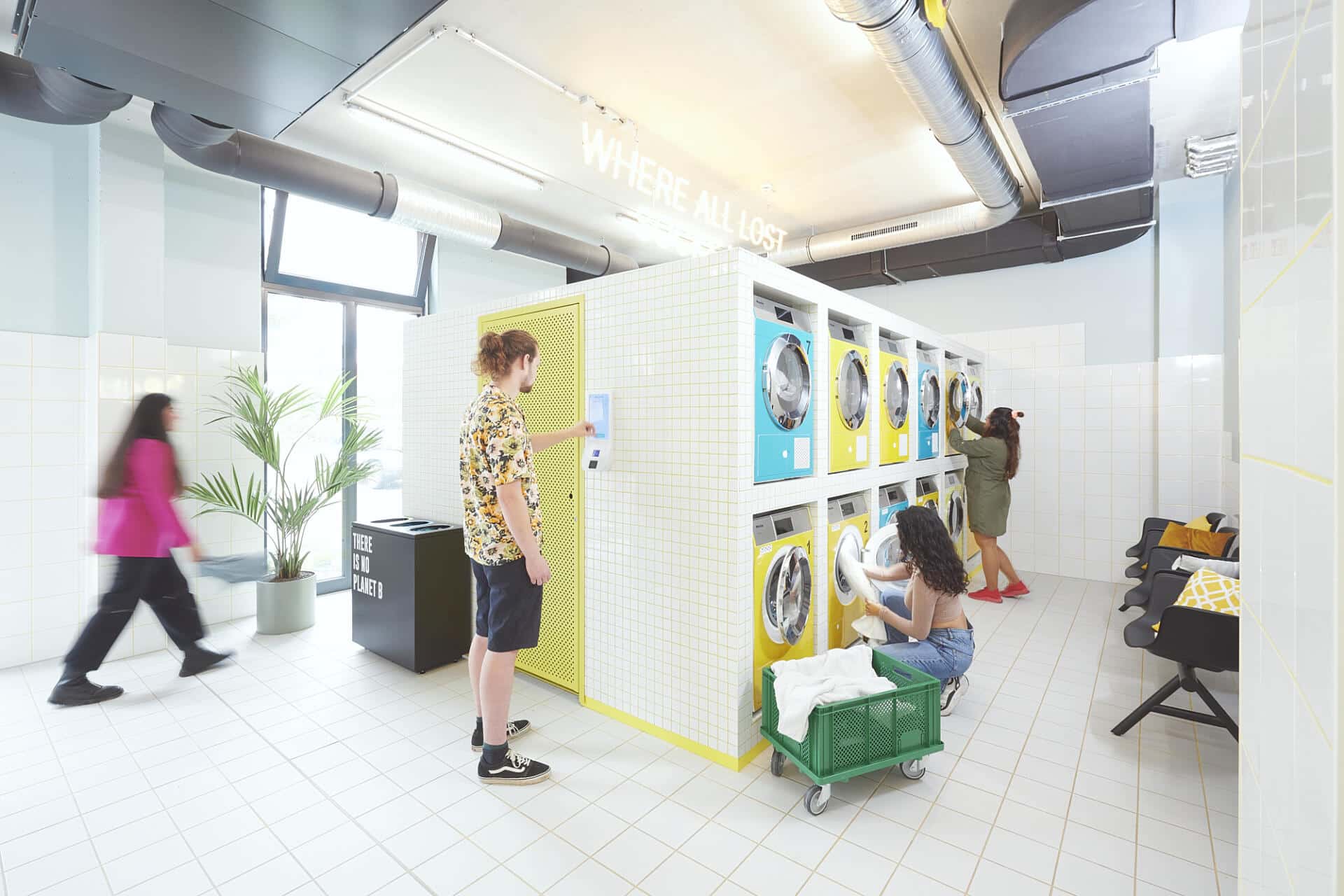 four students use colourful laundry machines at Basecamp Gottingen dormitory