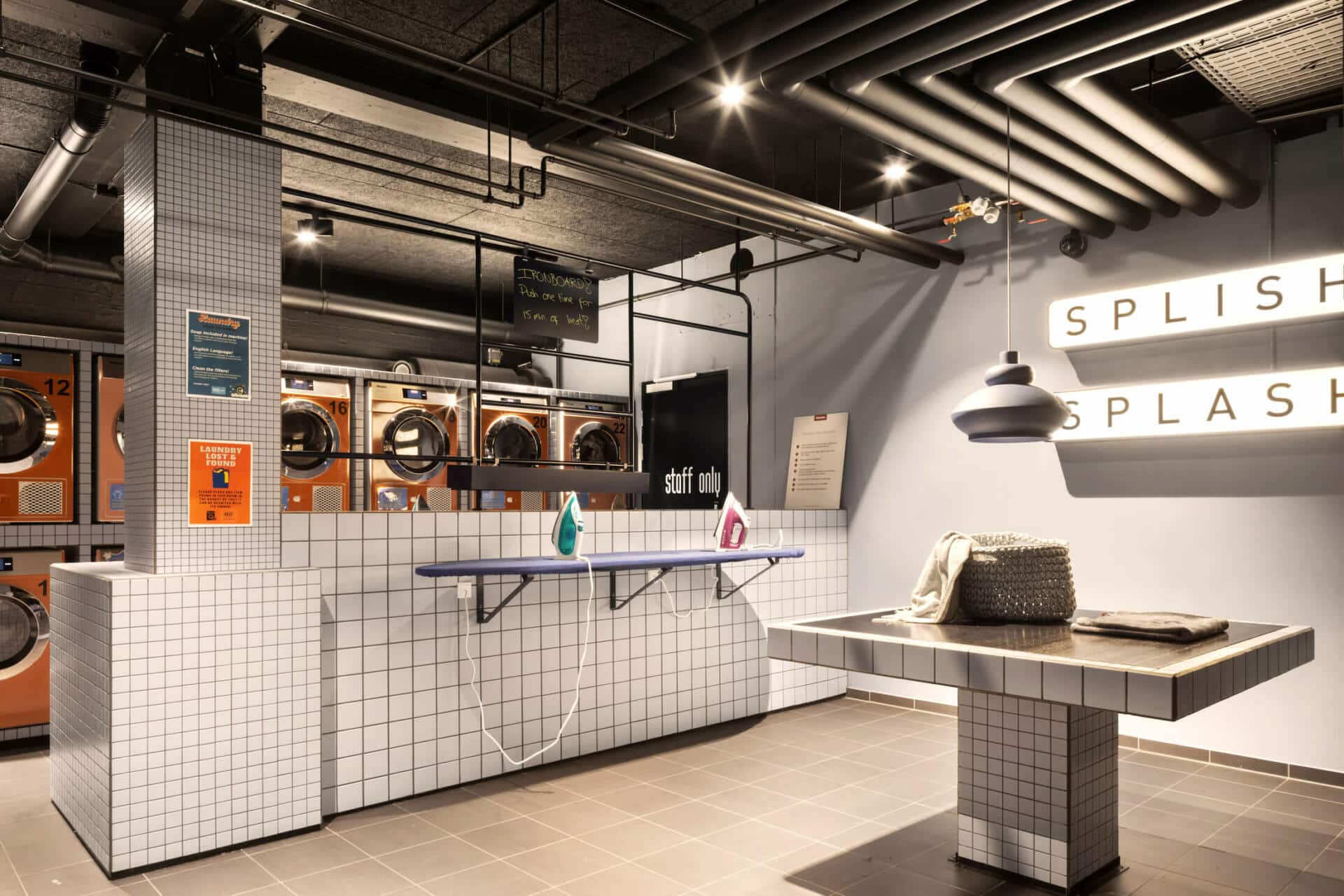 laundry room with washing machines, dryers and ironing areas at Basecamp Copenhagen student accommodation