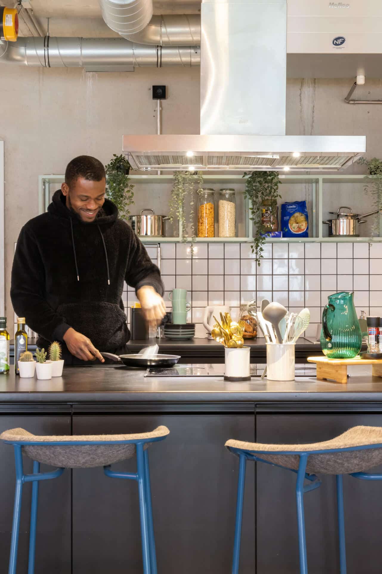 A student cooks in a common kitchen at Basecamp Potsdam student accommodation