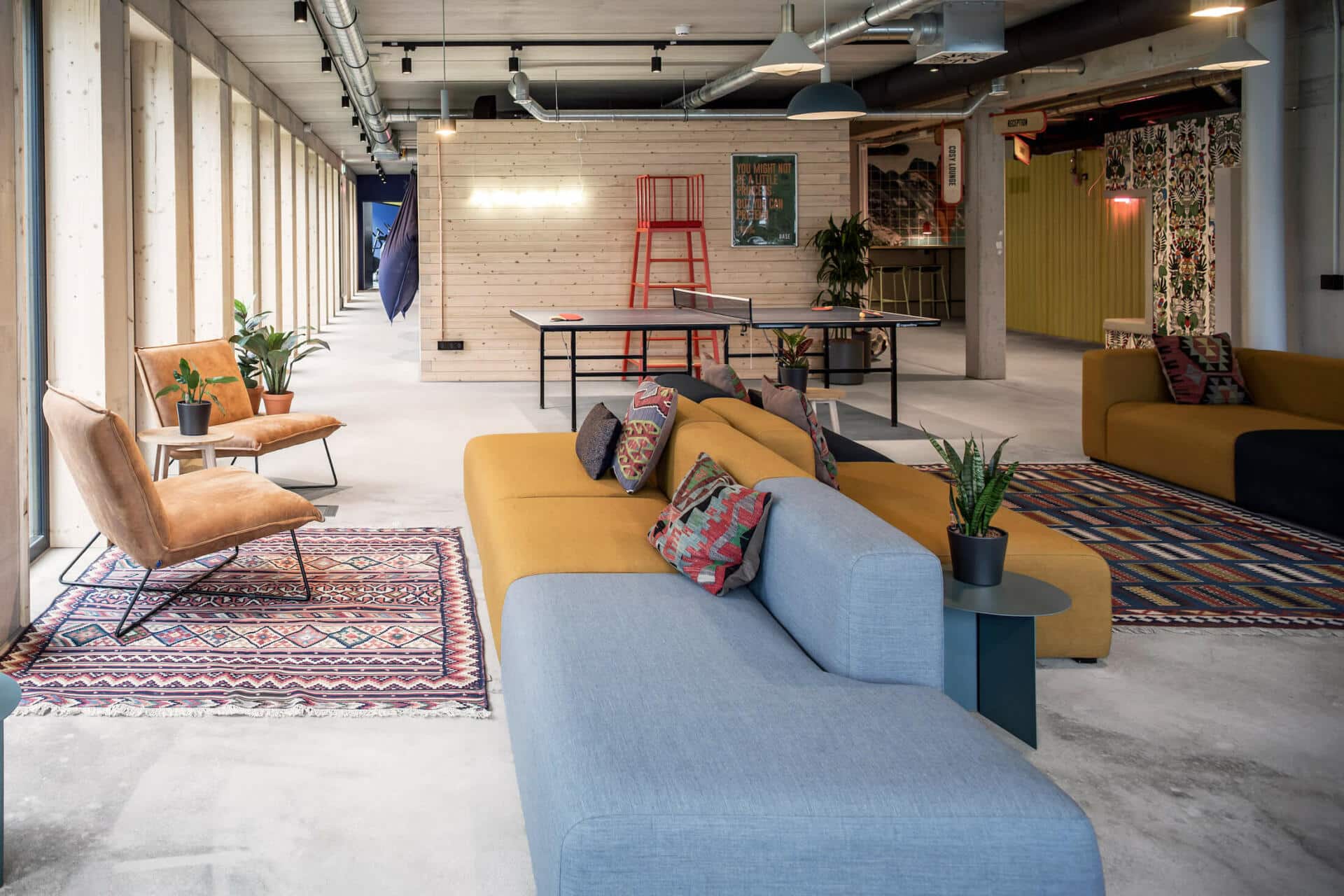 Large blue sofas and ping pong table in one of the event areas for student guests at Basecamp Potsdam accommodation