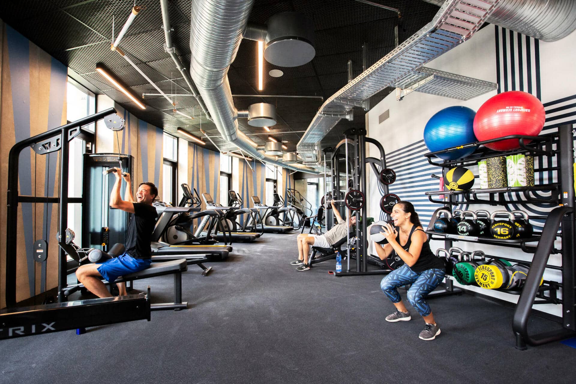 students lift weights and squat in the modern gym at Basecamp Lyngby student accommodation