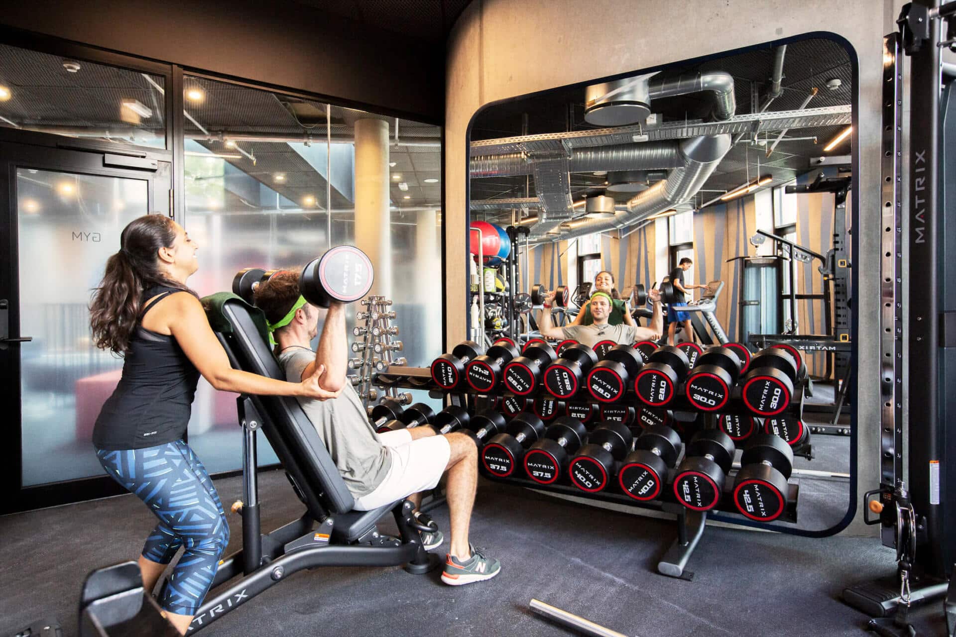 a student spots a fried who is lifting weights at Basecamp Lyngby's gym