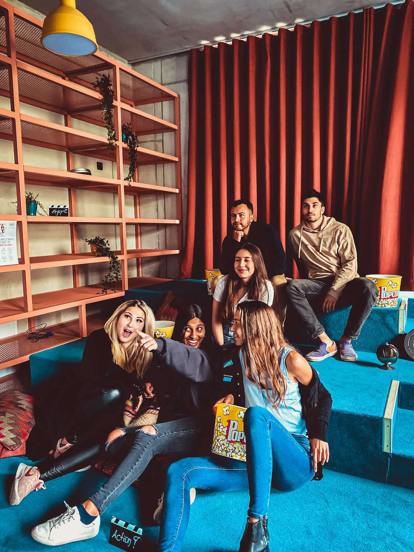 A group of students sit on blue sofas eating popcorn and watching a movie at our student accommodation in Leipzig