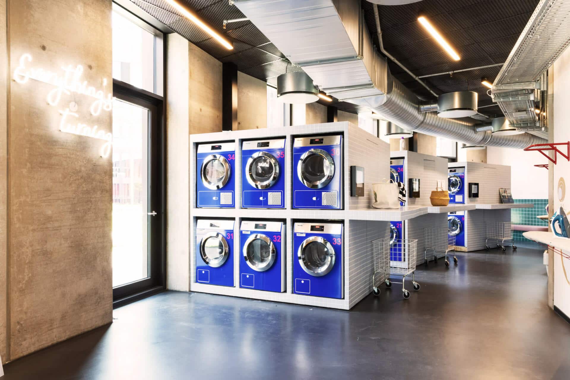 Laundry area with blue laundry machines at Basecamp Lyngby student housing