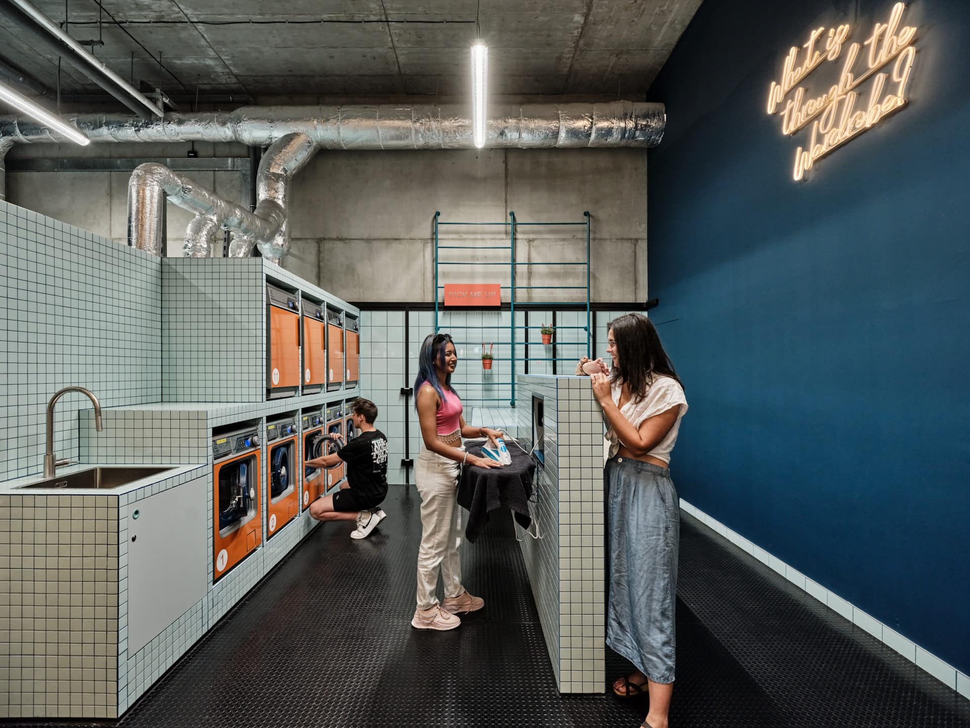 Students ironing and folding their clothes in the laundry room at Basecamp Katowice dormitory