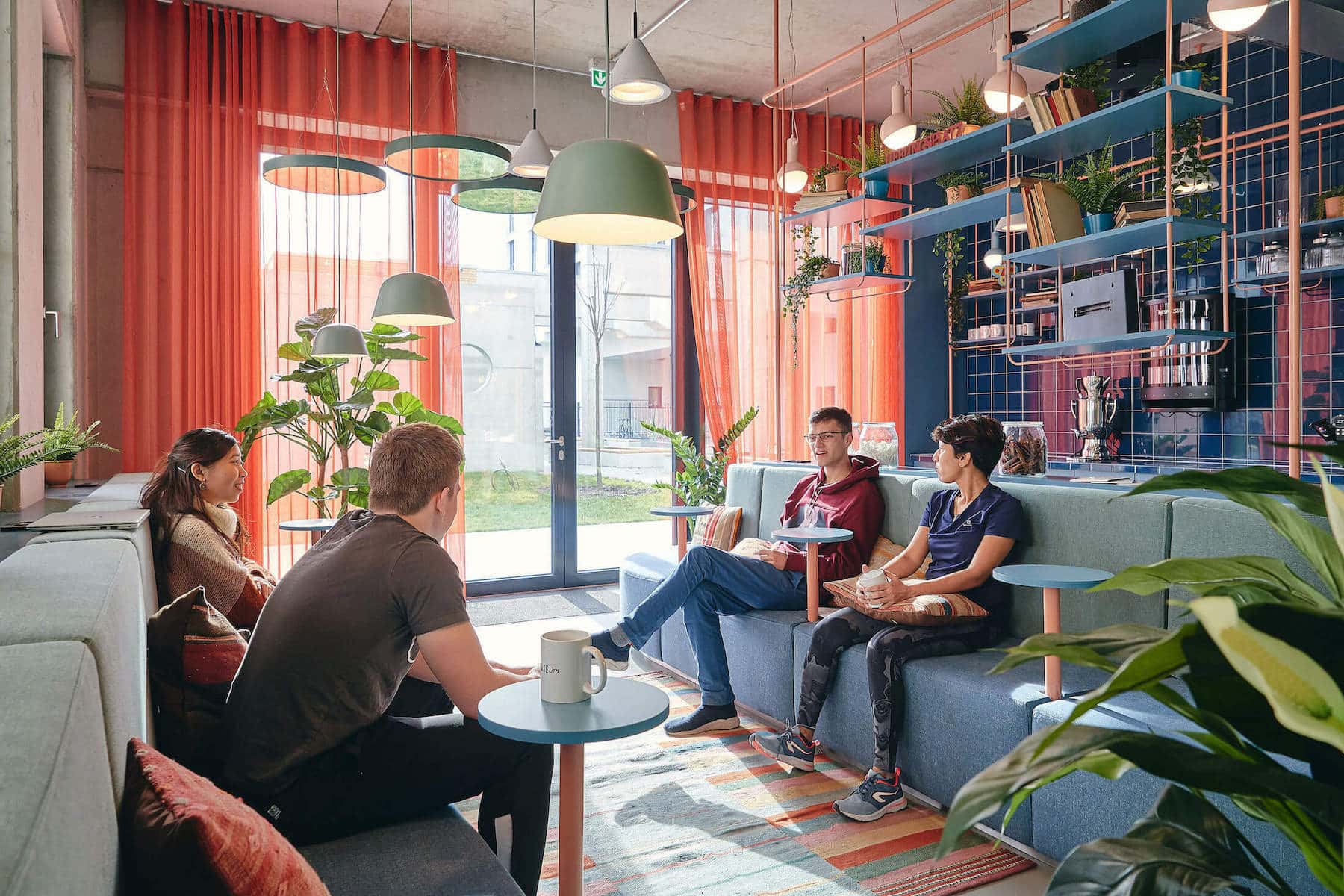 Students drinking a coffee and chatting on the comfortable sofas of the Relax Space at Basecamp Leipzig Student accommodation