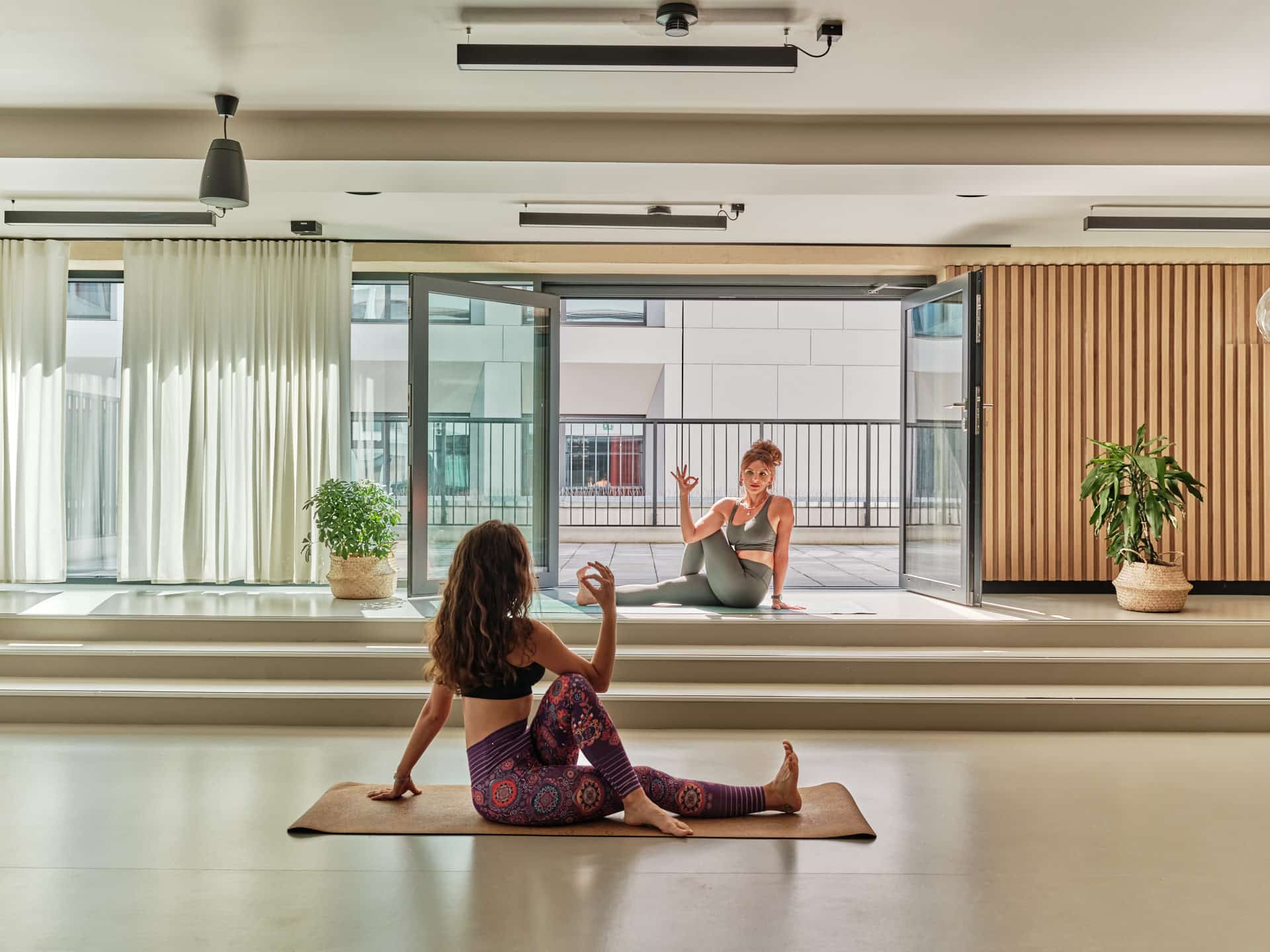 Two female students stretch in the Yoga room at Wroclaw Basecamp dormitory