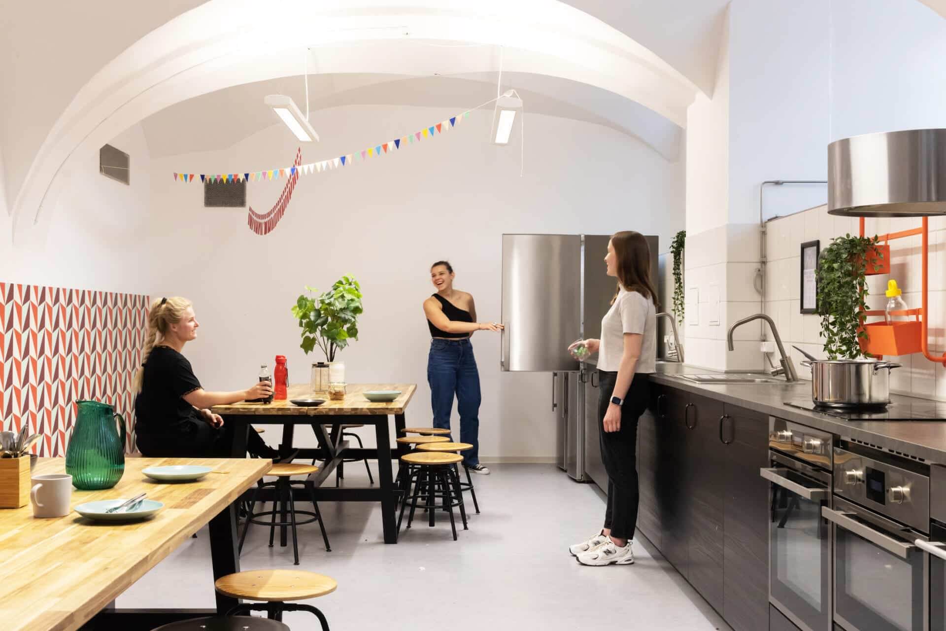 students chat and cook in the common kitchen at Basecamp Copenhagen student housing