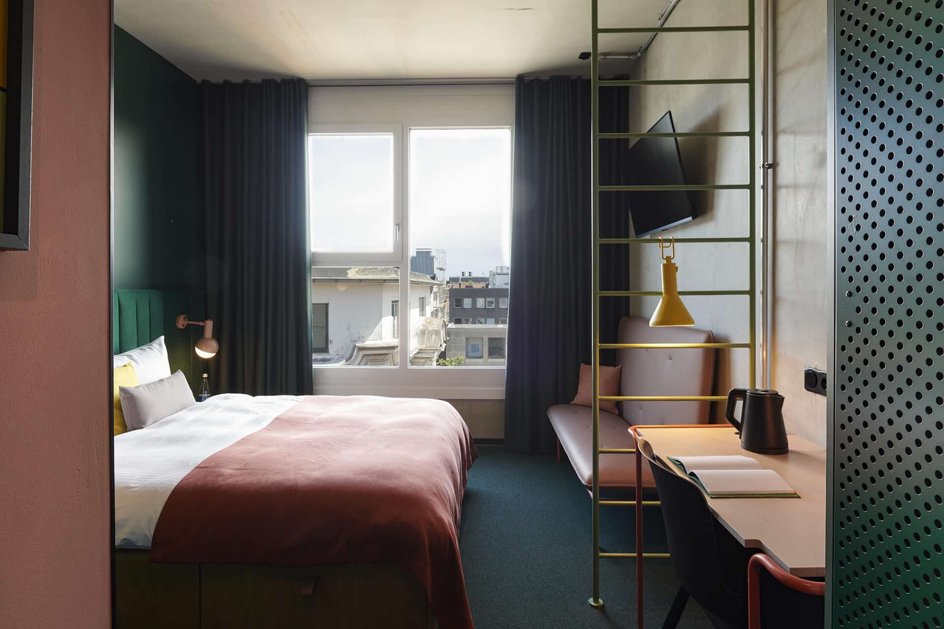 A hotel room with a bed, tv and a large window with views of Dortmund